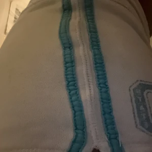 2000s vita shorts - Säljer ett par vita shorts med turkosa snören och tryck. Perfekta för en avslappnad stil. De har en låg midja och kort längd.