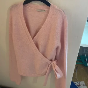 Rosa omlottkofta från Gina Tricot - Säljer en superfin rosa omlottkofta från Gina Tricot i premiumkvalitet. Den är mjuk och skön med långa ärmar och en söt knytning i sidan. Perfekt för både vardag och fest! 💖köpte den i butik och har bara haft på mig den 1 gång och helt slutsåld i alla storlekar🤍