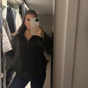 Mörkgrön teddyjacka - Säljer en supermysig mörkgrön teddyjacka med prislappen kvar . Den har en dragkedja framtill och långa ärmar. Perfekt för höst och vinter när du vill hålla dig varm och stilren. Jackan är i storlek dam M och passar perfekt till allt.