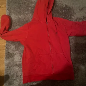 Röd hoodie från Ralph Lauren - Säljer en snygg röd hoodie från Ralph Lauren med dragkedja och klassisk logga på bröstet. Perfekt för en avslappnad stil med praktiska fickor framtill. Passar bra till både vardag och  Säljer eftersom jag inte använder den alls