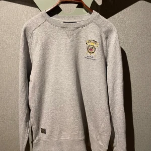 Grå sweatshirt från Morris R. Club - Snygg grå sweatshirt från Morris R. Club med ett snyggt tryck på bröstet. Ger en fräsch vardagslook!