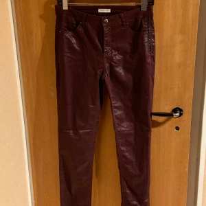 Vinröda byxor från Cache Cache - Snygga vinröda byxor från Cache Cache med en glansig finish och dragkedjedetalj vid fickorna 