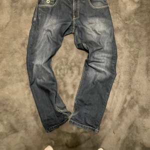 Blå jeans från South Pole - Säljer ett par blå jeans från South Pole med snygga kontrastsömmar och femficksdesign. Jeansen har en normal passform och är perfekta för en avslappnad stil.