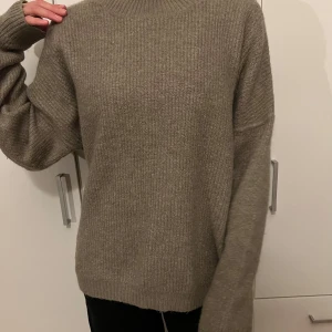 Beige stickad tröja - Mysig beige stickad tröja perfekt för kyliga dagar. Den har en avslappnad passform med långa ärmar och ribbade muddar vid ärmslut och nederkant. Perfekt för både höst och vinter!