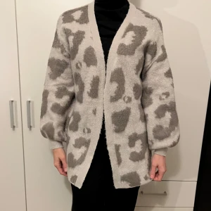 Grå leopardmönstrad kofta - Säljer en supermysig grå kofta med leopardmönster. Den är perfekt för höst och vinter, med långa ärmar och en loose passform. Koftan är i mycket bra skick och passar perfekt för att hålla dig varm och stilren. 🐆✨