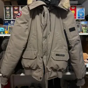 Säljer en snygg beige vinterjacka från Canada Goose i storlek S. Jackan har en avtagbar huva med pälsdetalj och flera praktiska fickor. Perfekt för kalla vinterdagar! 🧥❄️