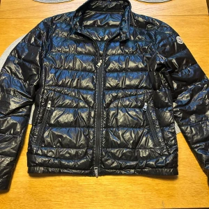 Moncler Acorus - Säljer en snygg svart pufferjacka från Moncler i mycket bra skick. Jackan har en glansig finish och är perfekt för höst och vinter. Perfekt för att hålla sig varm och stilren under kyliga dagar! Storlek 1 som motsvarar S, finns något defekt men syns inte. Skriv vid minsta fundering 💙