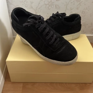 Svarta sneakers i mocka - Säljer ett par snygga svarta sneakers i mocka med vit sula. De har klassisk snörning och är perfekta för både vardag och fest. Skorna är i bra skick och passar till de flesta outfits. Perfekta för höst och vår! Pris kan diskuteras!!
