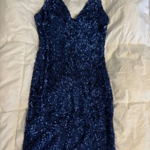 Glittrig klänning i blått och silver - Säljer två fantastiska glittriga klänningar, en i djupblå och en i silver. Perfekta för fest eller nyår! Båda är ärmlösa med en v-ringad design och täckta i paljetter ✨