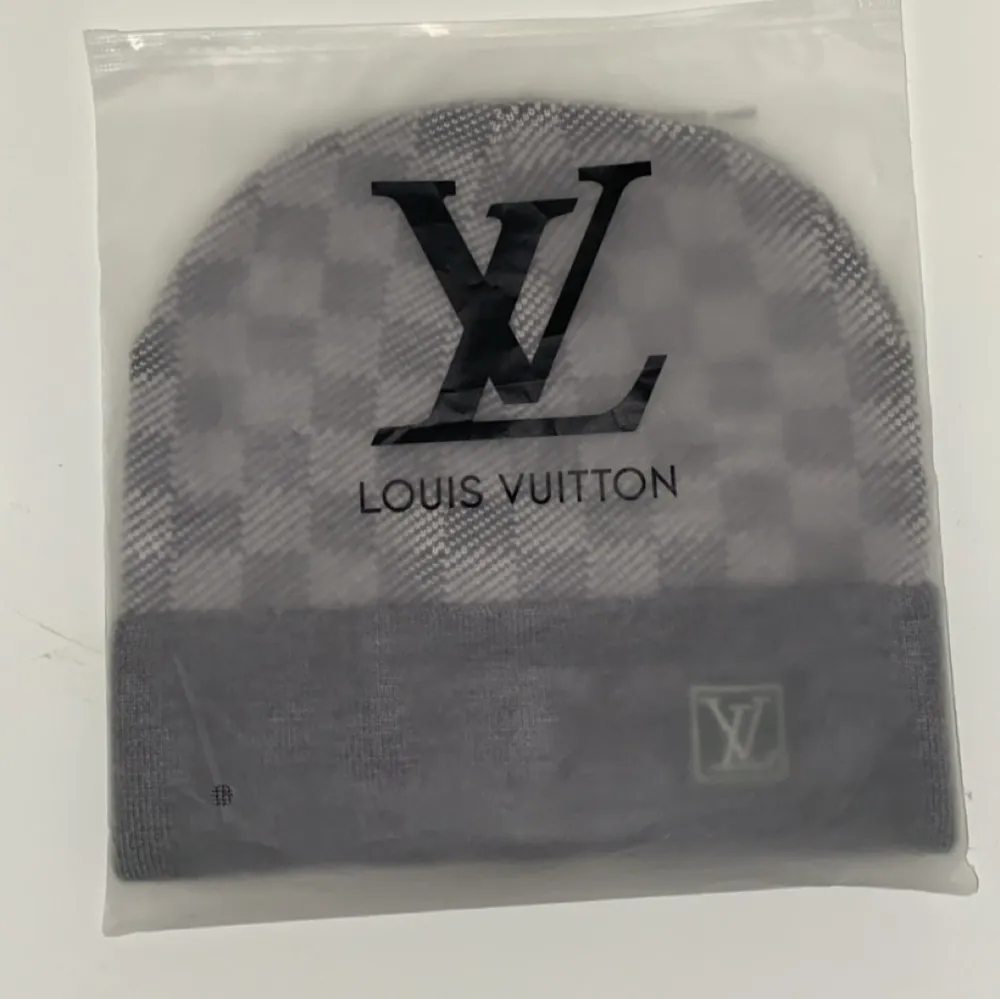 Snygg grå rutig mössa från Louis Vuitton i ett mjukt och bekvämt material. Den har en klassisk design med ett diskret LV-märke framtill. Perfekt för att hålla sig varm med stil under kyliga dagar.. Accessoarer.