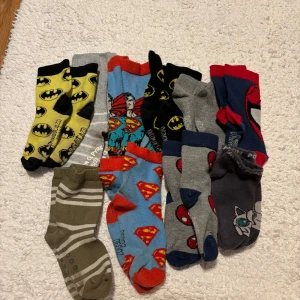 Strumpor barn  - Säljer ett gäng coola barnstrumpor med superhjältemotiv. De har olika färger och mönster, inklusive Batman och Superman. Perfekta för små äventyrare som älskar superhjältar! Strumporna är i fint skick, några kan va mer använda än andra. 