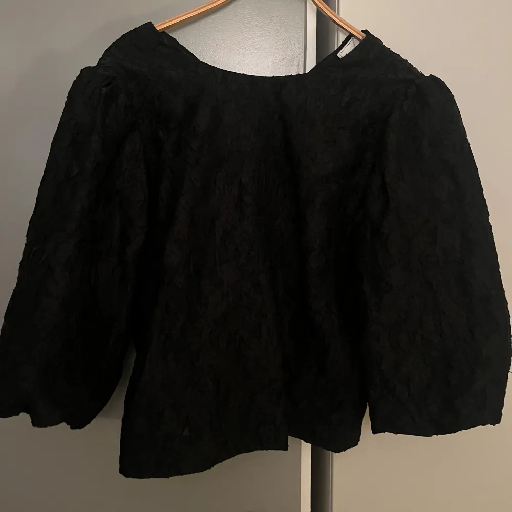 Snygg svart blus från Neo Noir i ett elegant material. Trekvartsärmad i storlek 42 men passar som en 40 också. I mycket bra skick. Yläosat.