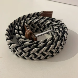 Flätat bälte - Säljer ett snyggt flätat bälte i svart, vit och grått med bruna läderdetaljer. Bältet är i hög kvalitet och i 9,5/10 skick, knappt använt. Passar till stora och små midjor då det har hål överallt. Tveka inte på att höra av er så svarar jag så fort jag kan!🤝🙌