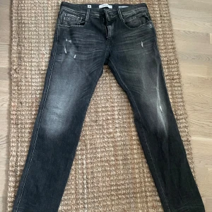 Replay jeans - Säljer ett par svarta jeans i bra skick. De har en snygg tvättad look med lite slitningar för en cool stil. Passformen är slimfit och de har en klassisk femficksdesign. Perfekta för både vardag och fest! Storlek är W34 L32. 
