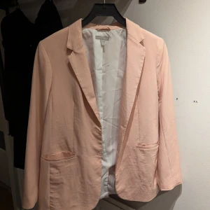 Ljusrosa kavaj från H&M - Säljer en stilren ljusrosa kavaj från H&M i storlek 36. Kavajen har en klassisk design med knappar framtill och två fickor. Materialet känns mjukt och bekvämt. 