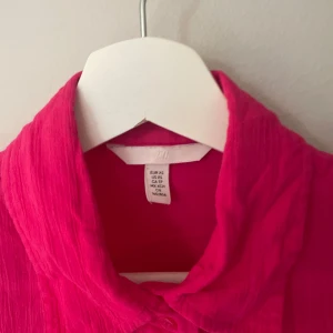 Rosa blus - Säljer en snygg rosa blus i storlek XS. Den har långa ärmar och knappar framtill. Perfekt för både vardag och festliga tillfällen. Materialet känns lätt och luftigt, vilket gör den skön att bära hela dagen. Passar bra till både jeans och kjol!