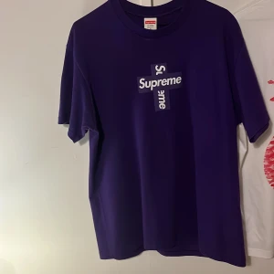 Supreme cross box purple tee - Säljer en snygg lila t-shirt från Supreme i 100% bomull. Den har en cool design med Supreme-loggan i vitt på framsidan. Perfekt för vardagsbruk eller att styla upp för en avslappnad look. T-shirten är i mycket bra skick och är tillverkad i USA. Köpt direkt från Supreme appen. (Inte fast pris)