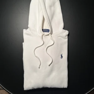 Polo Ralph Lauren Hoodie - Säljer en stilren vit hoodie från Polo Ralph Lauren i storlek M. Den har en klassisk design med en liten broderad logga på bröstet. Kostar nypris ca 1700kr. Säljer för 599kr.