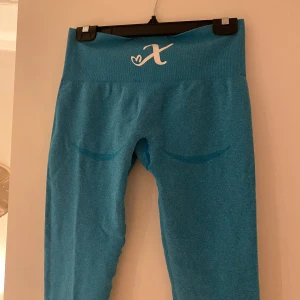 Träningstights - Blå träningstights från Xshapes (Peachy 2.0 Tights). Färgen finns ej kvar på hemsidan. Storlek L men passar M-L. Supersköna & stretchiga. Knappt använda & i superbra skick. Konturer vid rumpan som framhäver rumpan.