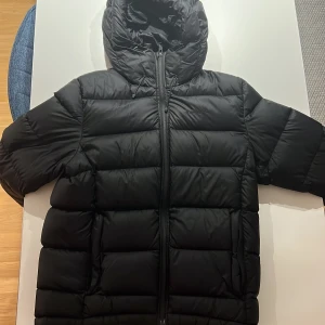 Svart pufferjacka från Everest - Säljer en svart pufferjacka från Everest i storlek S. Jackan är perfekt för kalla dagar med sin tjocka vaddering och huva. Den har en dragkedja framtill och är i mycket bra skick. Perfekt för vintern! ❄️