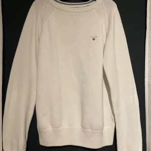Vit stickad tröja från Gant - Säljer en stilren vit stickad tröja från Gant med rund halsringning och ribbade muddar. Perfekt för en klassisk och avslappnad look. Tröjan har ett diskret Gant-emblem på bröstet.Storlek är 146-152= 11-12år!🩷