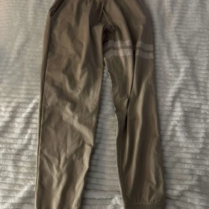 Beige mjukisbyxor med randig detalj - Säljer ett par bekväma beige mjukisbyxor med elastisk midja och randig detalj runt låren. Perfekta för en avslappnad stil. ⚠️ Ni betalar för frakt⚠️