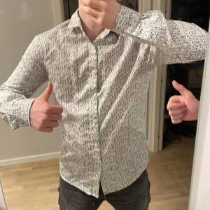 Blommig skjorta från Only & Sons - Säljer en snygg blommig skjorta från Only & Sons i slim fit. Skjortan är vit med ett färgglatt blommönster i blått och orange. Perfekt för både vardag och fest! Den är långärmad och gjord i ett bekvämt material. Passar perfekt till jeans eller chinos för en stilren look.