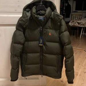 Ralph lauren jacka  - Säljer en snygg olivgrön dunjacka från Polo Ralph Lauren. Jackan är i nyskick skulle säga 9,7 i skick då den bara har används 2 gånger! Tags medföljer kvitto kan även tas fram vid köp. 