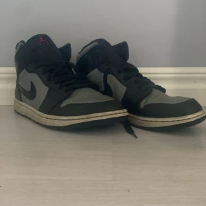 Nike Air Jordans i svart och grått - Säljer ett par Nike Air Jordans i svart och grått. De har en klassisk design med snörning och den ikoniska Jumpman-loggan i rött. Skorna är i grymt skick med lite slitage på sulan. Perfekta för både vardag och fest! Nypris på skorna är 2400kr