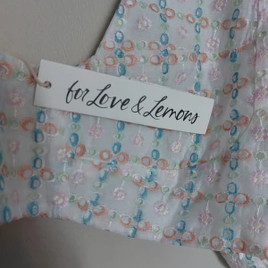 Topp från For Love & Lemons - Charmig blus från For Love & Lemons med ett färgglatt mönster i pastellfärger. Blusen har en djup v-ringning och puffiga ärmar som ger en romantisk känsla. Perfekt för en somrig look! Nypris 1400. Oanvänd med tags kvar. Xl men liten I storlek så ät en Medium så jag sätter den storleken i annonsen 