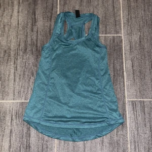 Turkos linnetopp från SOC - Säljer en snygg turkos linnetopp från SOC i mycket bra skick. Perfekt för träning eller sommaraktiviteter. Toppen är ärmlös och har en sportig design med brottarrygg för extra komfort. Materialet är mjukt och andas bra, vilket gör den idealisk för aktiva dagar.