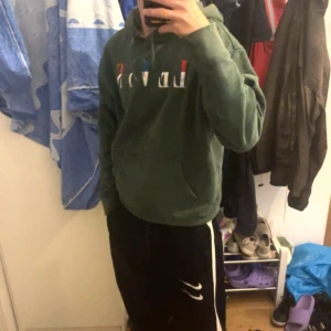 Grön hoodie med tryck - Säljer en grön hoodie med tryck på bröstet. Den är superbekväm och perfekt för chilliga dagar. Har en klassisk passform med långa ärmar och en praktisk ficka framtill. Perfekt för höst och vår men speciellt för vintern för den är skön och varm att ha på sig!