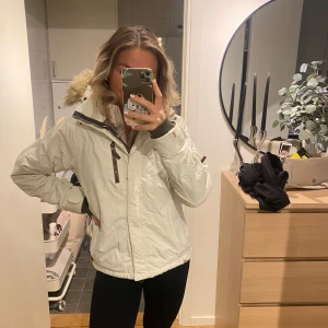 Vit vinterjacka - Säljer en vit vinter/skidjacka från Didriksons med pälskrage. Jackan har dragkedja och flera praktiska fickor för bland annat skidåkning. Storleken är mellan S och M.