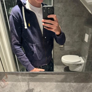 Ralph lauren zip hoodie - Snygg Ralph lauren hoodie. Tröjan har använts en del men är fortfarande i bra skick.tröjan är för övrigt ganska liten då den möjligtvis krympt i tvätten under åren så passar även xs Nypris 2300