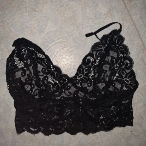 Svart spetstopp  - Strl ungefär S-M. Knäppning där bak 