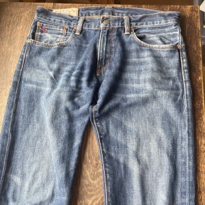 Riktigt snygga Ralph Lauren jeans - Size 30/32, marinblå. Lite vintage känsla, slitningar längst ner. Har använt dem ett antal gånger men nu passar de inte mig längre. Slim/straight fit. Lite små fickor. 