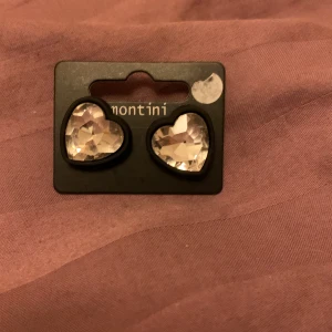 Hjärtformade örhängen från Montini - Säljer ett par supersöta hjärtformade örhängen från Montini. De är glittriga och perfekta för att ge lite extra bling till din outfit. Passar perfekt till både vardag och fest! 💖