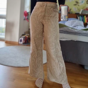 Mönstrade begie byxor - Säljer ett par supercoola beige byxor från urban outfitters BDG. De är högmidjade och har en loose passform. Passar både vardag och fest. De är lite uppsydda i benen för att passa mig som är 170ish.Går nog även att ha low waist beroende på midjemått.
