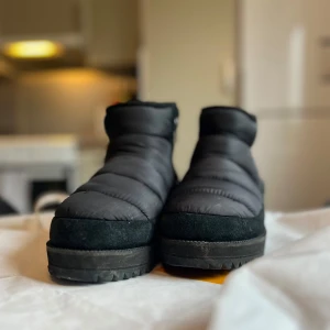 Ugg Ridge Mini - Boots Ridge Mini från UGG i fint skick. Skorna är i en mix av textil och mocka med dragkedja på sidan och ull på insidan. Storlek 39. 