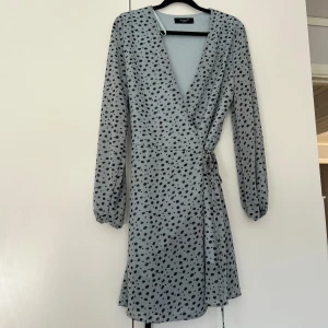 Omlottklänning - Blå omlottklänning med svarta prickar 
