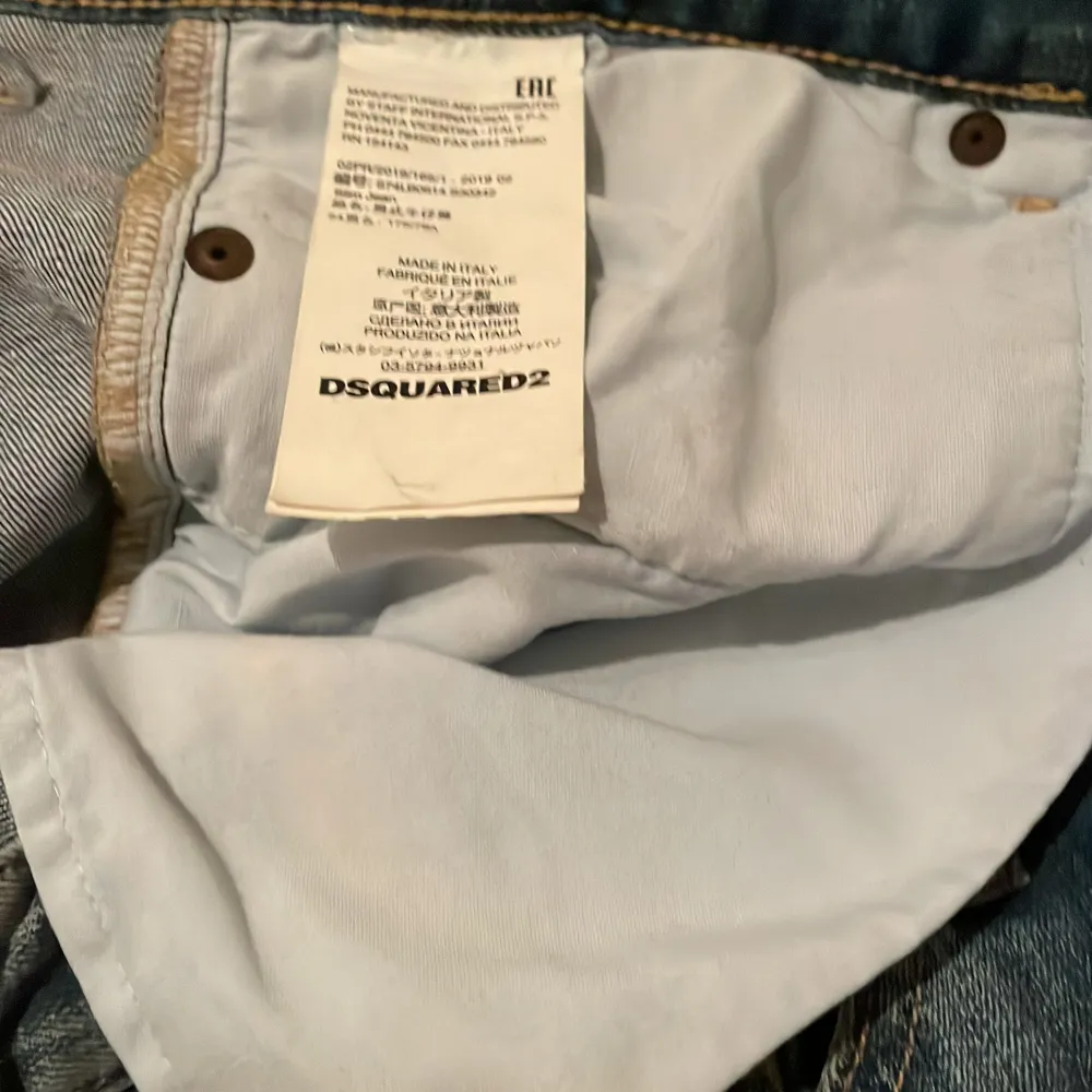 Säljer ett par blå jeans från Dsquared2 med slitna detaljer och patchar. Jeansen har en broderad lönnlöv på bakfickan och knappar i gylfen. Perfekta för en avslappnad stil. Knappt använda. Farkut & Housut.
