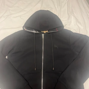 Svart zip från burberry - Säljer denna Svarta zip up från burberry eftersom den är liten på mig, storlek Medium men är liten i storleken och passar small