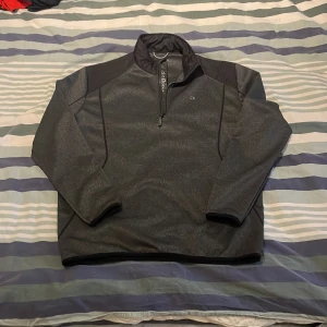 Svart fleece tröja med dragkedja från Calvin Klein  - Säljer en svart fleece tröja med halv dragkedja och hög krage. Perfekt för kyliga dagar med sin mjuka och varma känsla. Tröjan har långa ärmar och en enkel design. Pris går alltid att förhandlas!