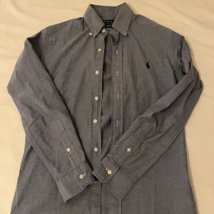 Ljusblå skjorta från Ralph Lauren - Snygg ljusblå skjorta från Ralph Lauren med klassisk krage och knappar framtill. Skjortan är använd ett fåtal gånger och i perfekt skick. Nypris cirka 1400 kr. Storlek XS men passar S.