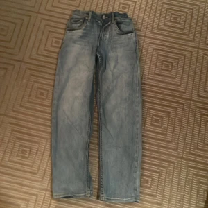 Blå jeans från Levi's - Säljer ett par klassiska blå Levi's jeans med baggy fit. De har en knappgylf och fem fickor. Perfekta för en avslappnad stil.