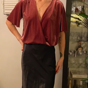 Vinröd omlottbody i sammet från Zara - Elegant vinröd omlottbody i mjuk sammet med kortärmad design. Klänningen har en djup v-ringning och vida korta ärmar.