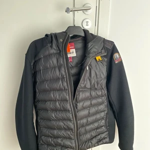 Parajumper cardigan - Snygg svart cardigan från Parajumpers med dragkedja och huva. Jackan har ett quiltat mönster på framsidan, Perfekt för kyliga dagar. Ett dugg billigare Vid snabb och smidig affär.