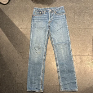 Levis 501 jeans i ljusblå denim - Klassiska Levis 501 jeans i ljusblå denim. De har en rak passform och är lågmidjade med fem fickor och knappgylf. Perfekta för en avslappnad stil.