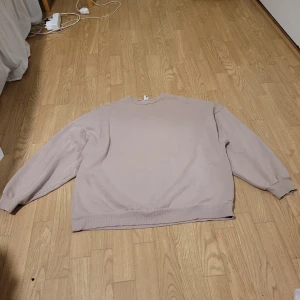 Beige tröja från NLY Trend - Säljer en stilren beige tröja från NLY Trend. Tröjan har en klassisk design med långa ärmar och rund halsringning. Perfekt för en avslappnad look. Den är väldigt oversized så någon som använder storlek L kan använda den.