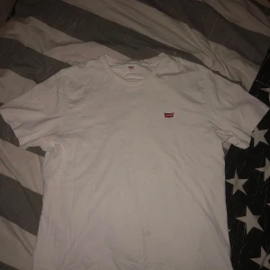 Vit t-shirt från Levi's - Klassisk vit t-shirt från Levi's med liten röd logga på bröstet. Perfekt för en avslappnad stil.